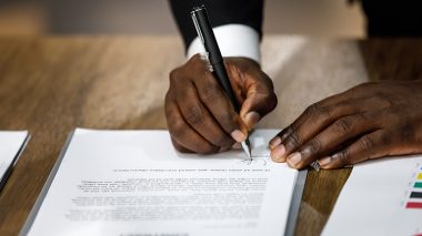 Hand holding a pen signing a document