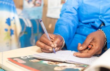 Image of hands using a pen to complete a form