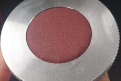 Silver metal circle with red sandpaper at the centre of the circle.