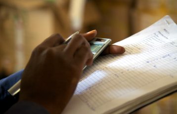 Picture of a hand entering numbers into a calculator while holding a document